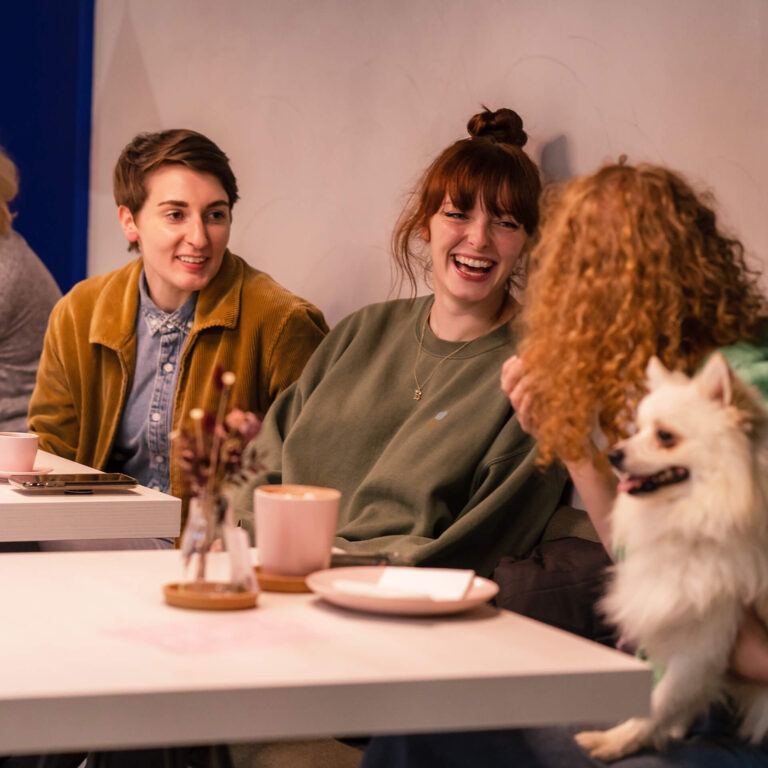 Group of people with dog laughing at cafe