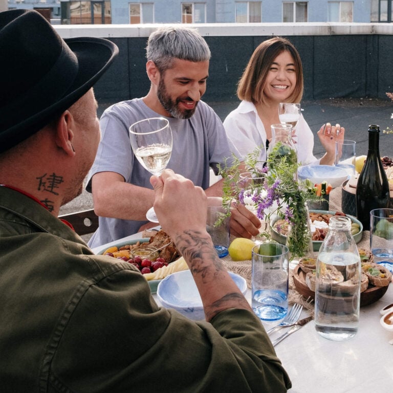 Group of people having dinner outside with drinks and flowers