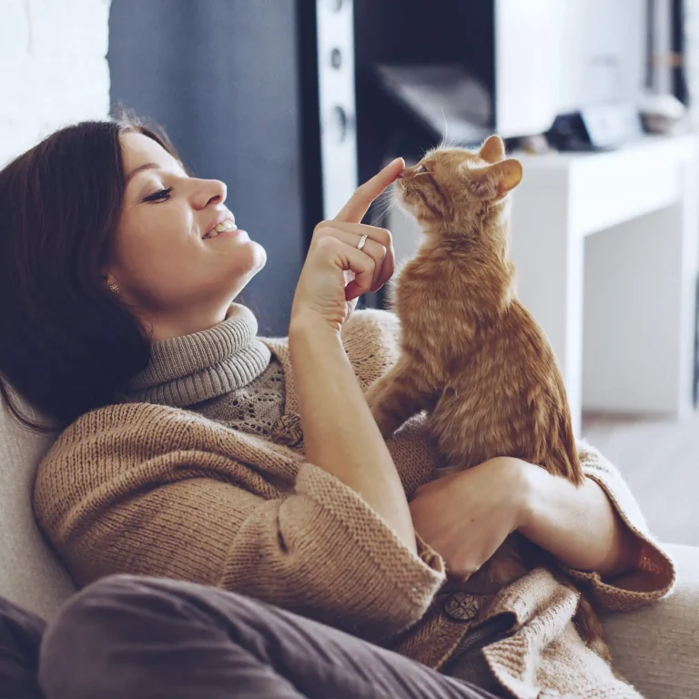 Woman with orange kitten, relaxing in her apartment.
